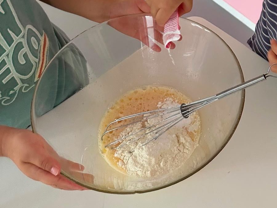 Enfant participant à un atelier cuisine aux P'tites Graines : préparation d'une pâte dans un saladier