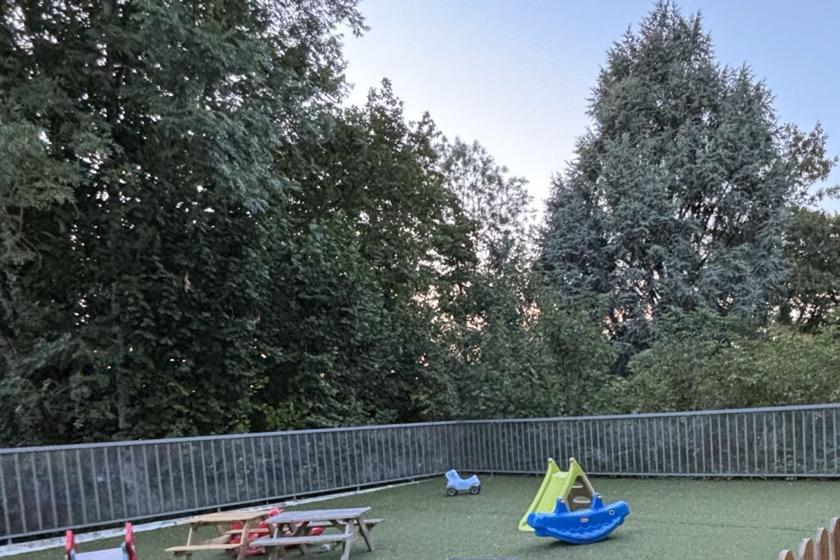 Espace extérieur sécurisé de la micro-crèche Les P'tites Graines à Olivet, entouré d'arbres